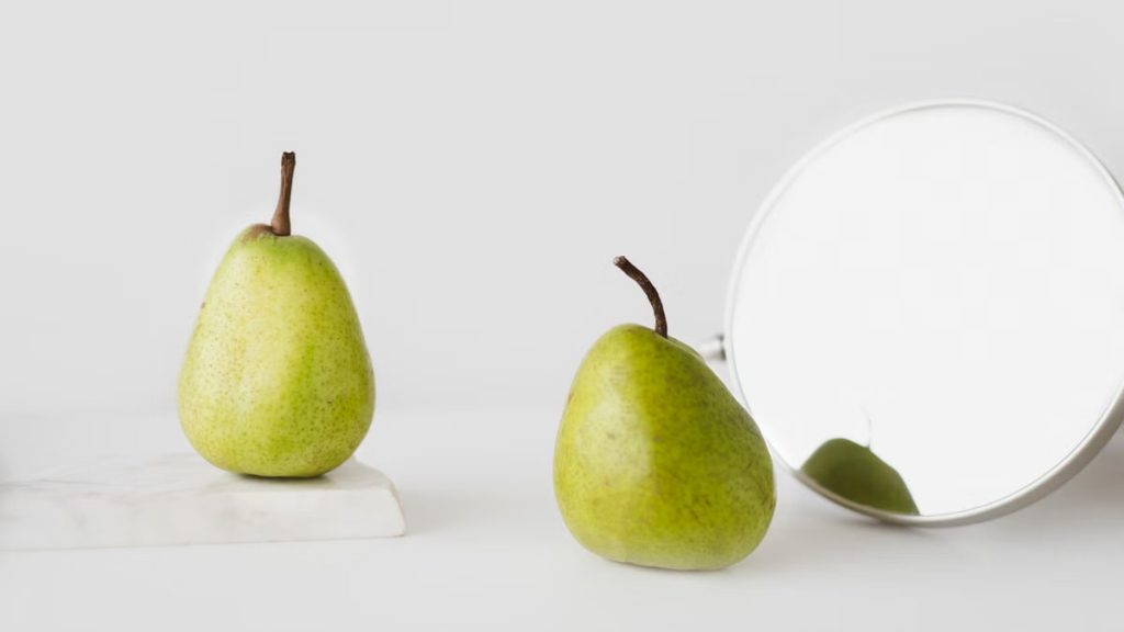 Two green pears with reflective mirror, perfect for health and design concepts.